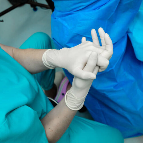 Interlocked fingers of the doctor's hands in sterile gloves. Selective focus.